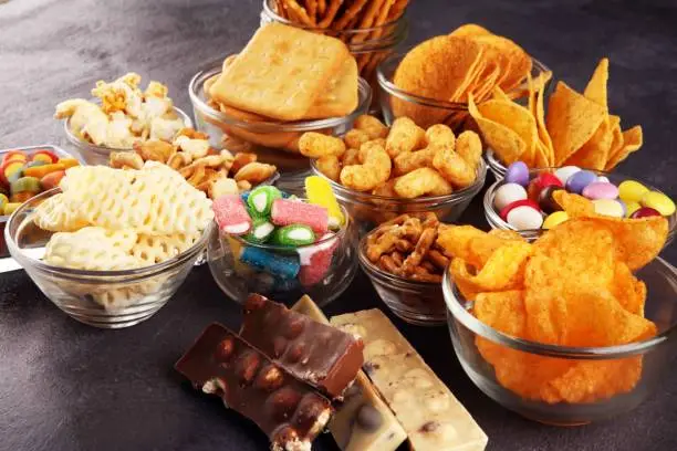 Salty snacks. Pretzels, chips, crackers in glass bowls. Unhealthy products. food bad for figure, skin, heart and teeth. Assortment of fast carbohydrates food.