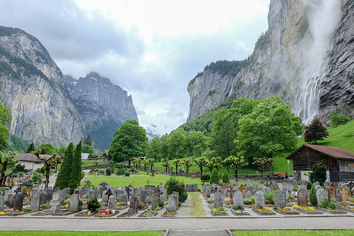 Jun 2016, Lauterbrunnen Valley, Switzerland. Cemetery in Lauterbrunnen with Staubach waterfall in background.