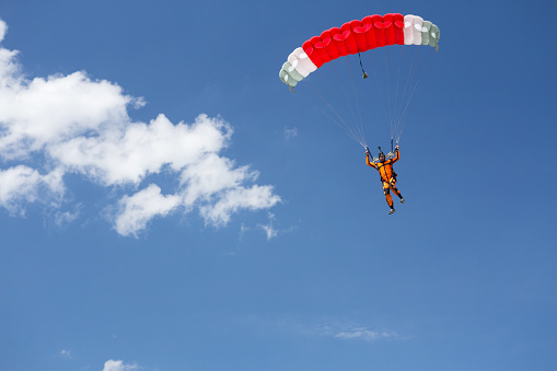 A person rises into the air attached to a parachute that is held above the water surface by a boat. Parasailing