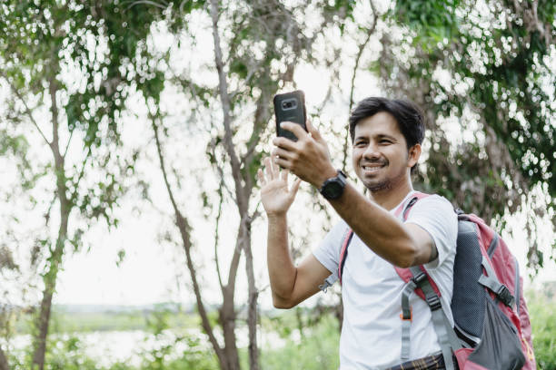 istock Young Asian man traveling backpacker video calling in the forest 1250261090
