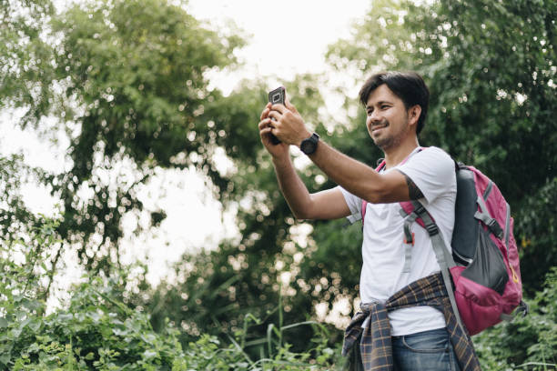 istock Young asien man backpack take photo with a smartphone in forest 1250261216