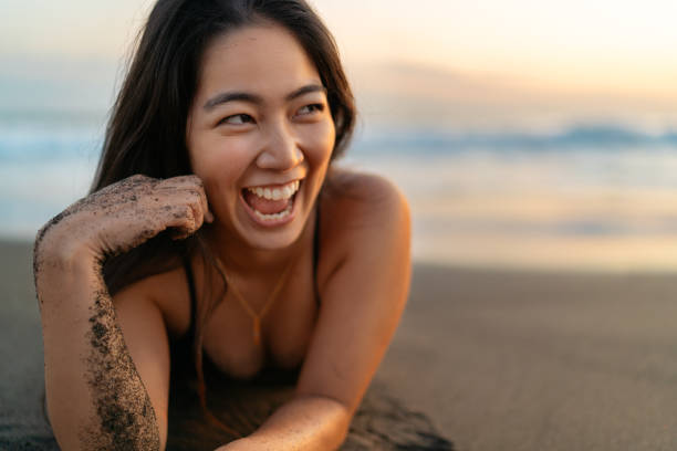 istock Young woman in bikini lying on her front on beach and laughing happily 1250263384