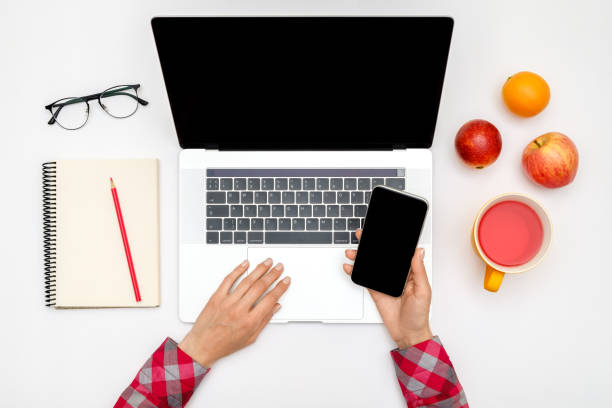 istock Home office workspace mockup. Laptop with blank screen, hands and accessories on white background. Flat lay. Top view 1250267717