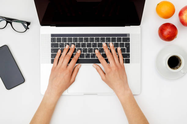 istock Top view of beautiful woman 's hands using laptop placed on white desktop. Flat lay 1250267737