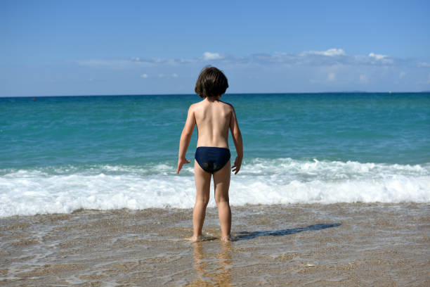 Child sit on beach and play in sea on summer vacation