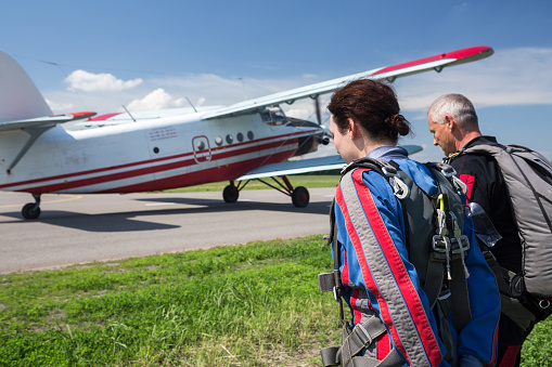 A tandem of an instructor and a woman go to the plane for a parachute jump.