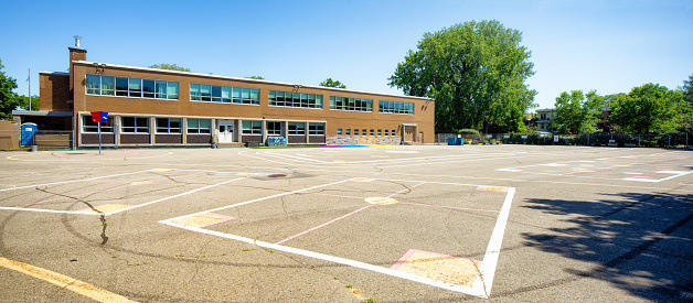 Montreal elementary school empty schoolyard panoramic view on a clear Summer day with game zone markings on the pavement.
