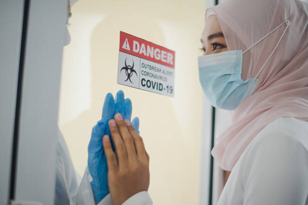 Young Asian woman Muslim meet family sister is doctor behind glass window of negative pressure room at hospital which sad and felling care, miss and love. Pandemic of corona virus, COVID19 concept. la joven asiática musulmana conocer hermana de la familia es médico detrás de la ventana de cristal de la sala de presión negativa en el hospital que la atención triste y de la tala, la señorita y el amor. pandemia del virus corona, concepto covid19.