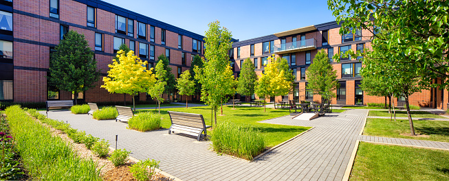 Panoramic view of an idyllic Montreal apartment complex with a landscaped courtyard in late Springtime on a clear sunny day.