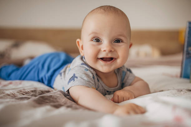 hermoso niño acostado en la cama y sonriendo - niños bebés fotografías e imágenes de stock