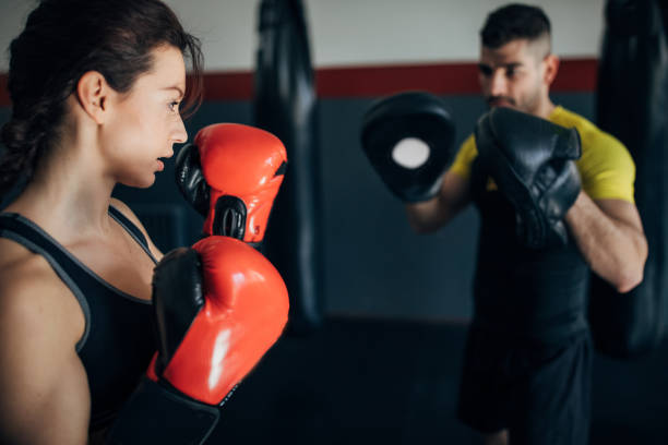 istock Female kickboxer sparring with her coach in the gym 1250274821