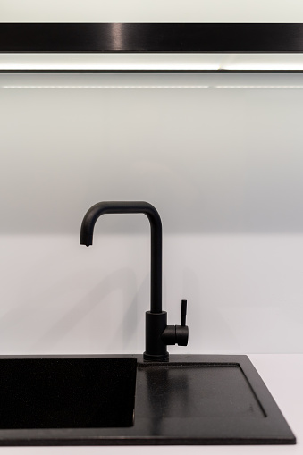 Vertical photo of element modern kitchen room with new interior design, contemporary black sink and water tap against white copy space wall