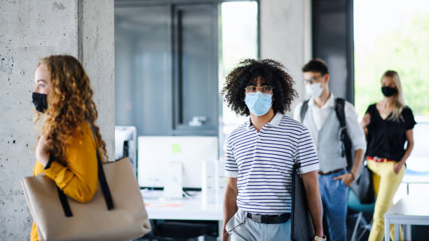 istock Young people with face masks back at work in office after lockdown, walking. 1250279695