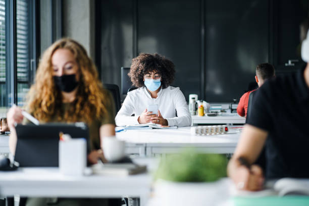 istock Young people with face masks back at work or school in office after lockdown. 1250279767