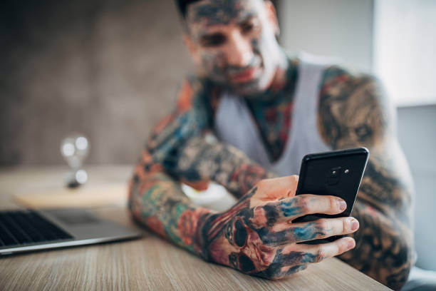 istock Man with whole body covered in tattoos using smart phone at home 1250281085