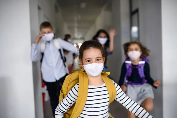 Group of cheerful children going home from school after covid-19 quarantine and lockdown, running.