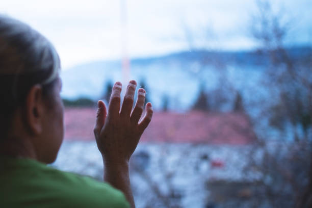 istock Alone woman looking out of window 1250286836