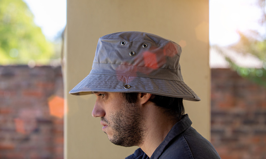 young man with a hat next to a wall walking outdoors