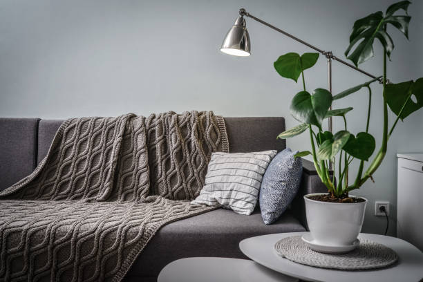 istock Grey couch with cushions, knitted plaid  and  floor lamp 1250290685