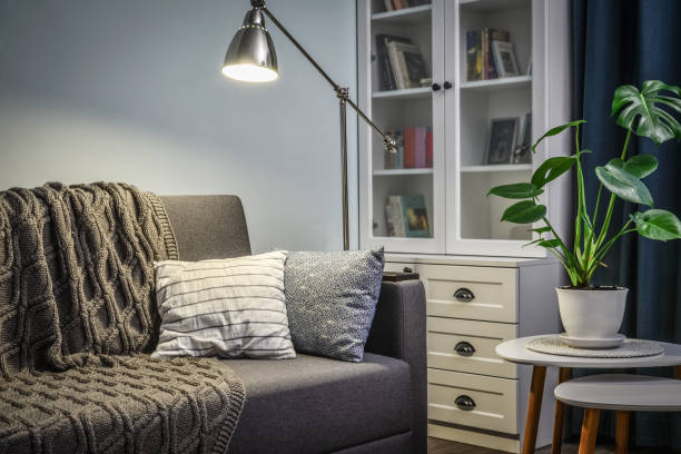 istock Grey couch with cushions, knitted plaid  and  floor lamp 1250290709