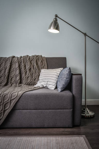 istock Grey couch with cushions, knitted plaid  and  floor lamp 1250290715