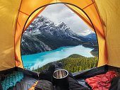 Camping with holding cup in yellow tent open with Peyto Lake in Icefields Parkway