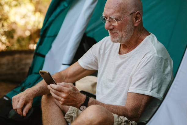 istock Senior man using phone at campsite 1250291672