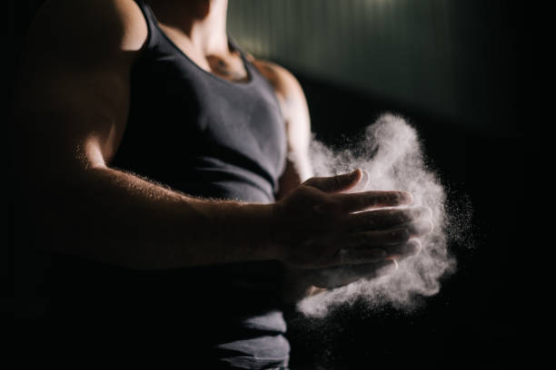 istock Close-up of unrecognizable strong man clapping hands with talc and preparing for workout at gym. 1250293080