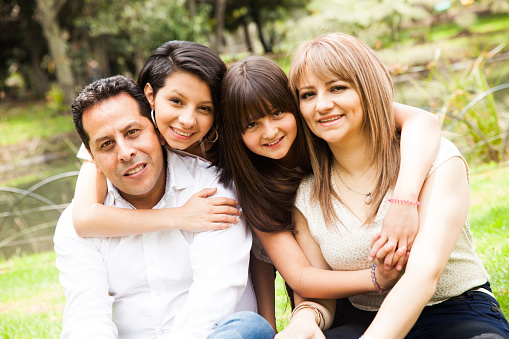 Portrait of a happy Latin American family at the park looking at the camera smiling - lifestyle concepts