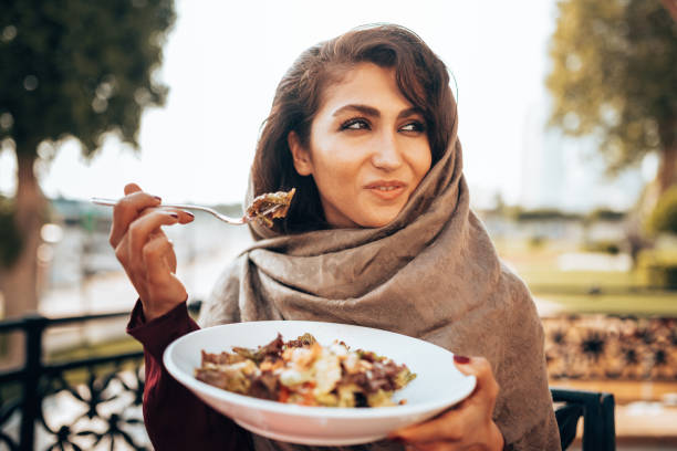 mujer árabe comiendo en el restaurante - women islam middle eastern ethnicity arabic style fotografías e imágenes de stock