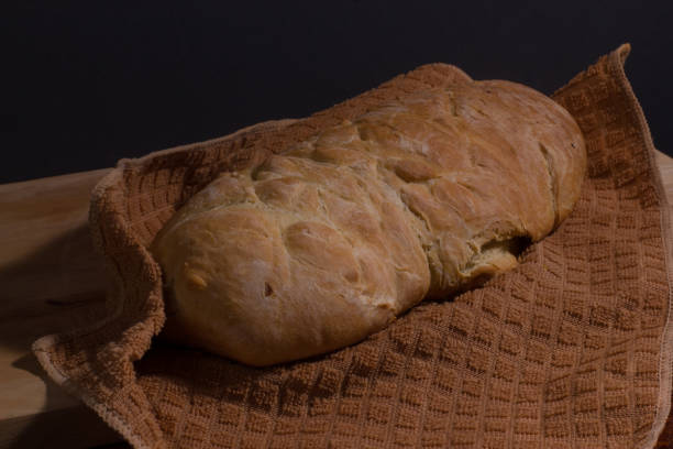 pão caseiro em uma toalha de pano marrom na tábua de corte de madeira. - brown bread bread cutting board full length - fotografias e filmes do acervo