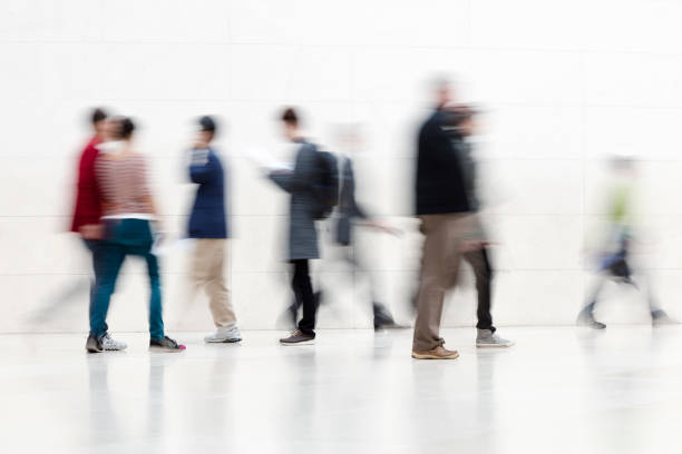 istock Group of Blurred People Walking on White Hallway 1250296963