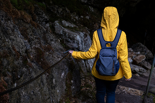 Woman in Yellow raincoat entering the Cave of Velika Ledenica in Paradana, Slovenia.