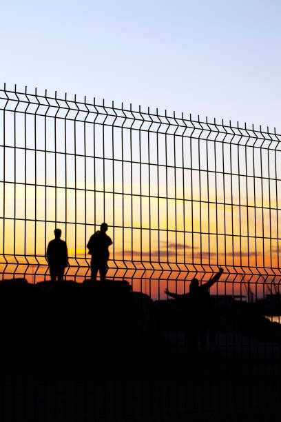 istock People Silhopuette Behind the Grate Fence 1250302240