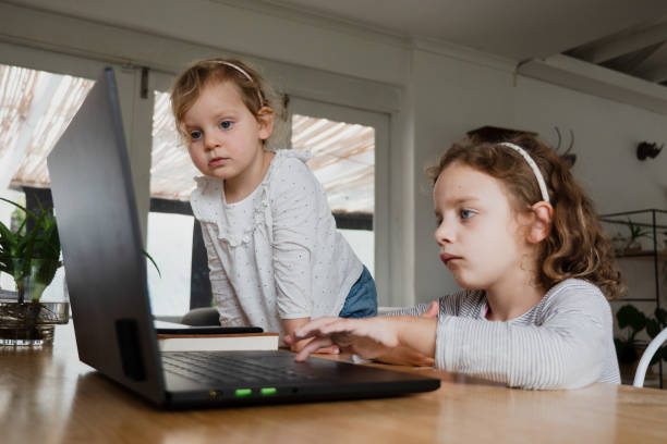 istock Young sisters on the computer together watching the screen 1250304068