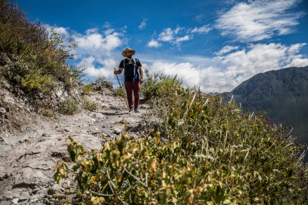 young man is walking in a canyon, big mountains, clouds and blue sky