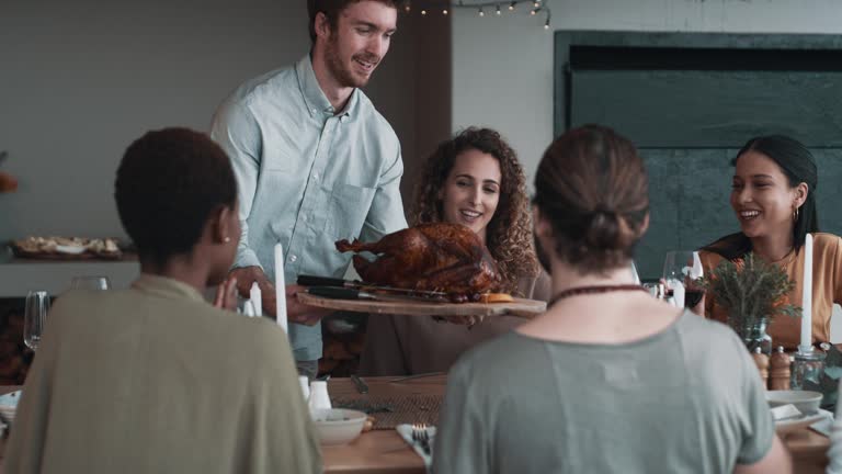 4k video footage of a man carrying a roast turkey to a table during a dinner party with friends outdoors