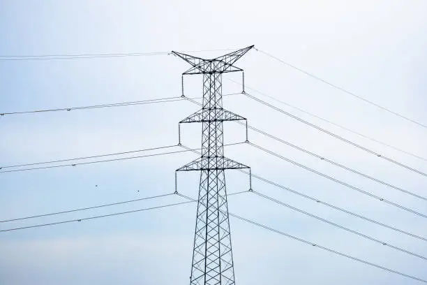 Large electrical tower connected by cables with a blue sky with clouds in the background