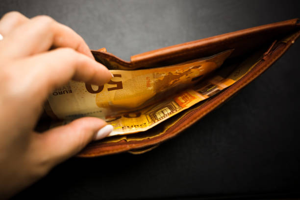 istock Woman's hand holding a black wallet with euro money. 1250317558