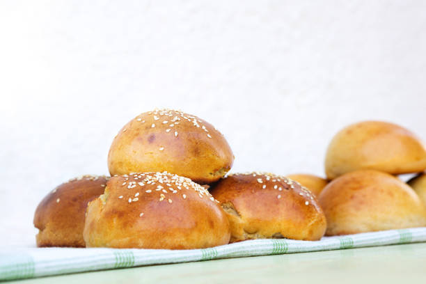 Fresh homemade burger buns with sesame on kitchen towel in sunny day.