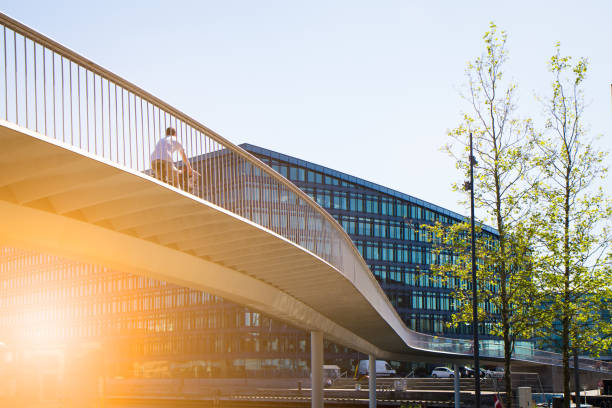 Copenhagen cityscape Bicycle bridge for the many commuters cycling on the numerous bike lanes over the canals. Take ride and through the modern architecture constituting an impressive cityscape with contemporary office buildings and residential flats at the up class oceanfront at Islands Brygge and Kalvebod Brygge in Copenhagen, Denmark people on bridge stock pictures, royalty-free photos & images