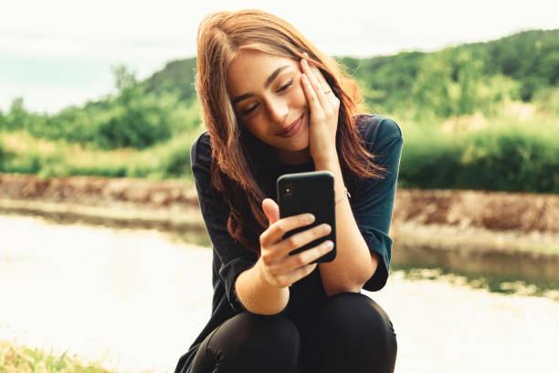 lächelnde junge frau auf videoanruf mit handy - photographing smart phone friendship photo messaging stock-fotos und bilder