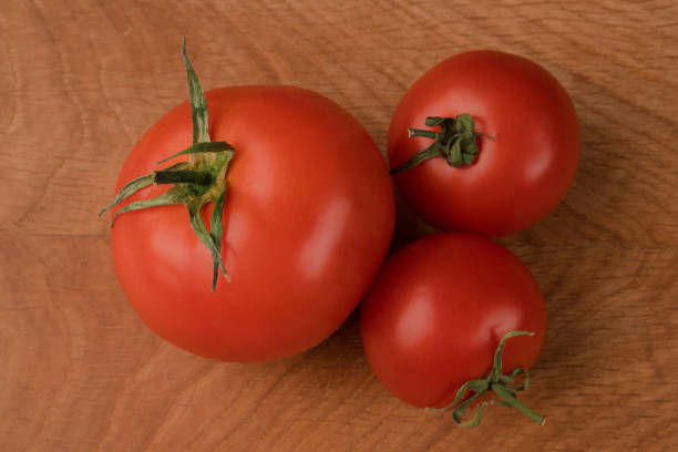 istock Three whole tomatoes on a wooden board 1250325893