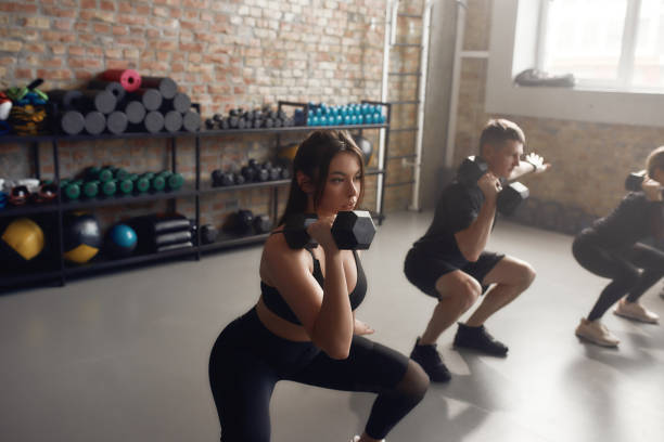 istock The best training. Young athletic woman lifting dumbbell while having workout at industrial gym. Group training, teamwork concept 1250327898