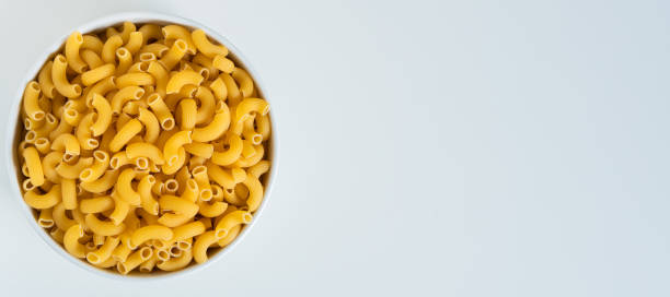 istock Raw dry uncooked Elbow Macaroni pasta spaghetti on white background. Good for basil tomato pesto sauce Homemade fresh Italian food organic whole wheat vegan spaghetti noodle for a healthy meal 1250328877