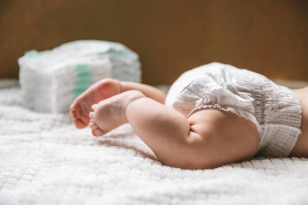ребенок в подгузнике в возрасте двух месяцев и стопка подгузников. как выбрать детские подгузники - подгузник стоковые фото и изображения