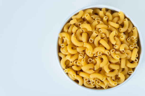 istock Raw dry uncooked Elbow Macaroni pasta spaghetti on white background. Good for basil tomato pesto sauce Homemade fresh Italian food organic whole wheat vegan spaghetti noodle for a healthy meal 1250328905