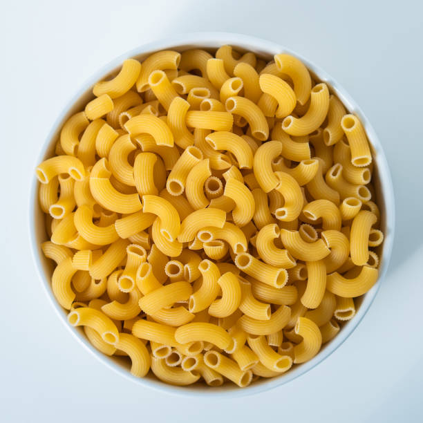 istock Raw dry uncooked Elbow Macaroni pasta spaghetti on white background. Good for basil tomato pesto sauce Homemade fresh Italian food organic whole wheat vegan spaghetti noodle for a healthy meal 1250328906