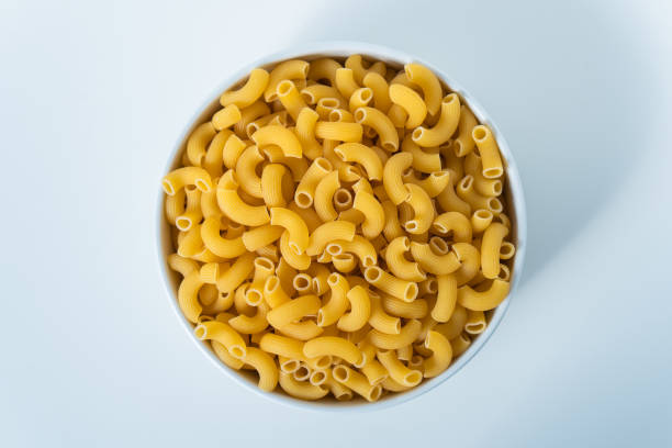 istock Raw dry uncooked Elbow Macaroni pasta spaghetti on white background. Good for basil tomato pesto sauce Homemade fresh Italian food organic whole wheat vegan spaghetti noodle for a healthy meal 1250328914