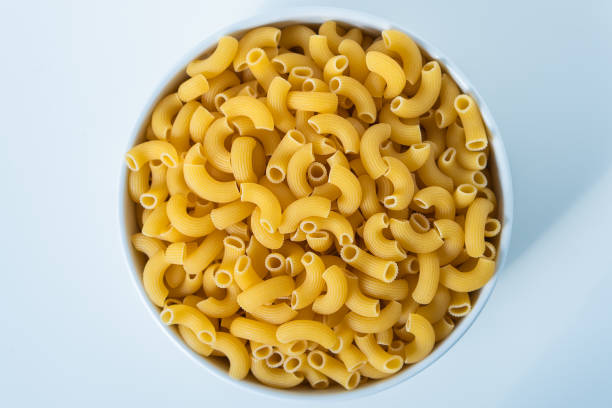 istock Raw dry uncooked Elbow Macaroni pasta spaghetti on white background. Good for basil tomato pesto sauce Homemade fresh Italian food organic whole wheat vegan spaghetti noodle for a healthy meal 1250328947